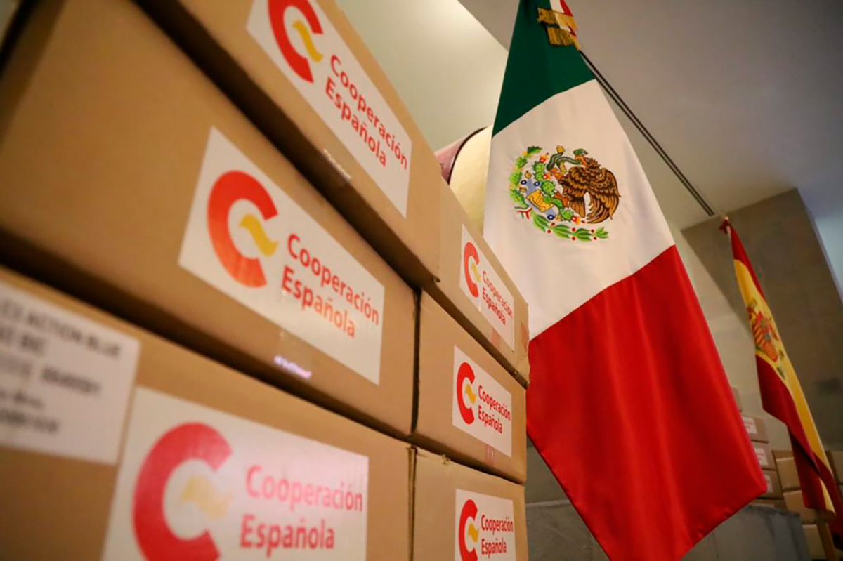 cajas de material humanitario al lado de una bandera mexicana